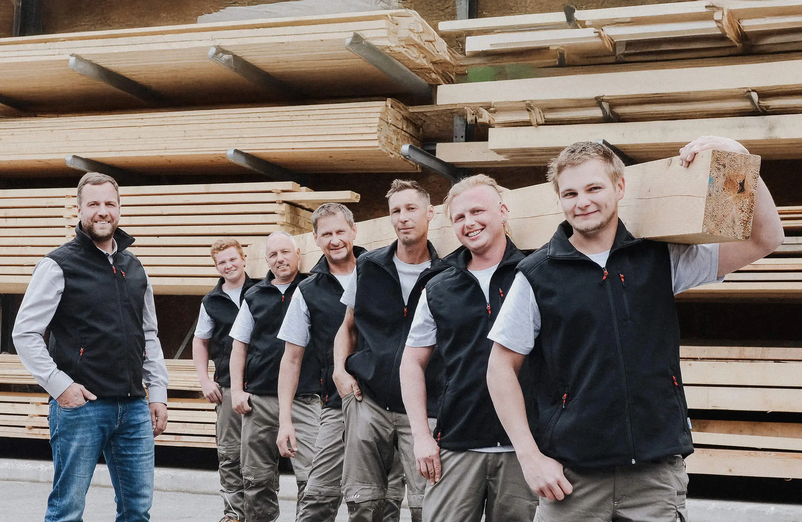 Mitarbeiterteam von RM Holzbau vor dem Holzlager des Unternehmens