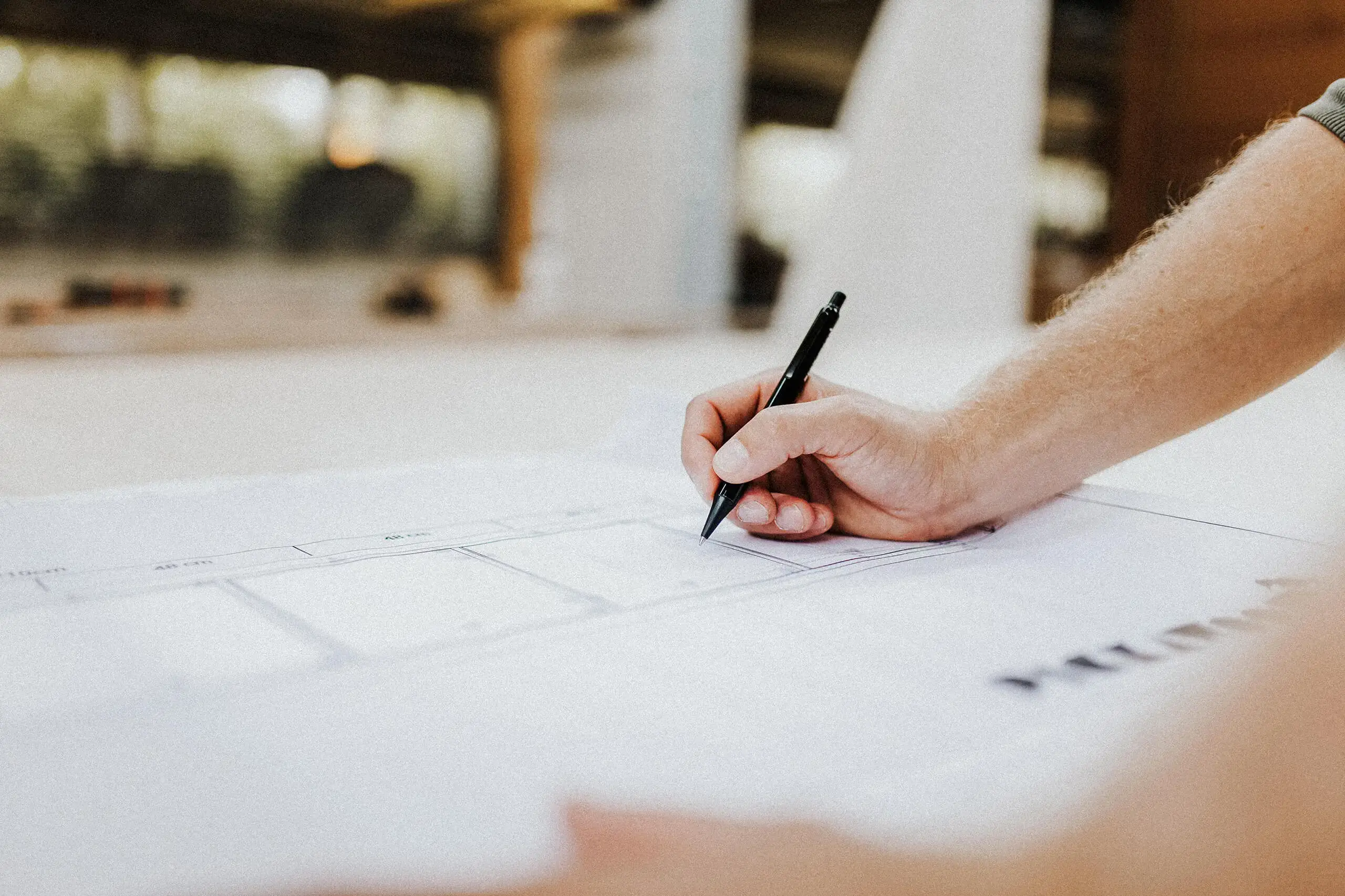 Hand bei der Arbeit mit einem Bauplan – Symbol für präzise Holzbauplanung bei RM Holzbau
