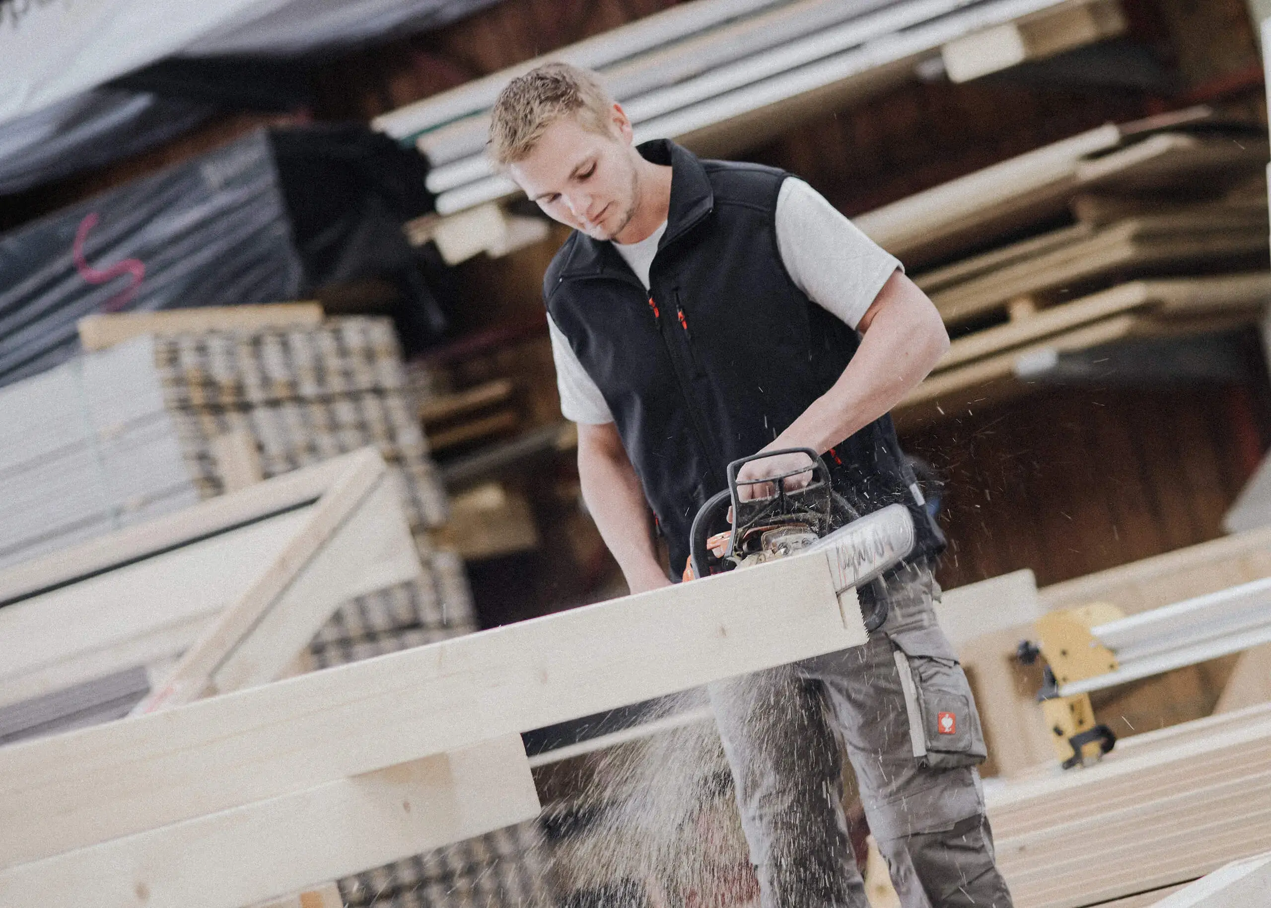 Mitarbeiter von RM Holzbau beim Sägen eines Holzbalkens
