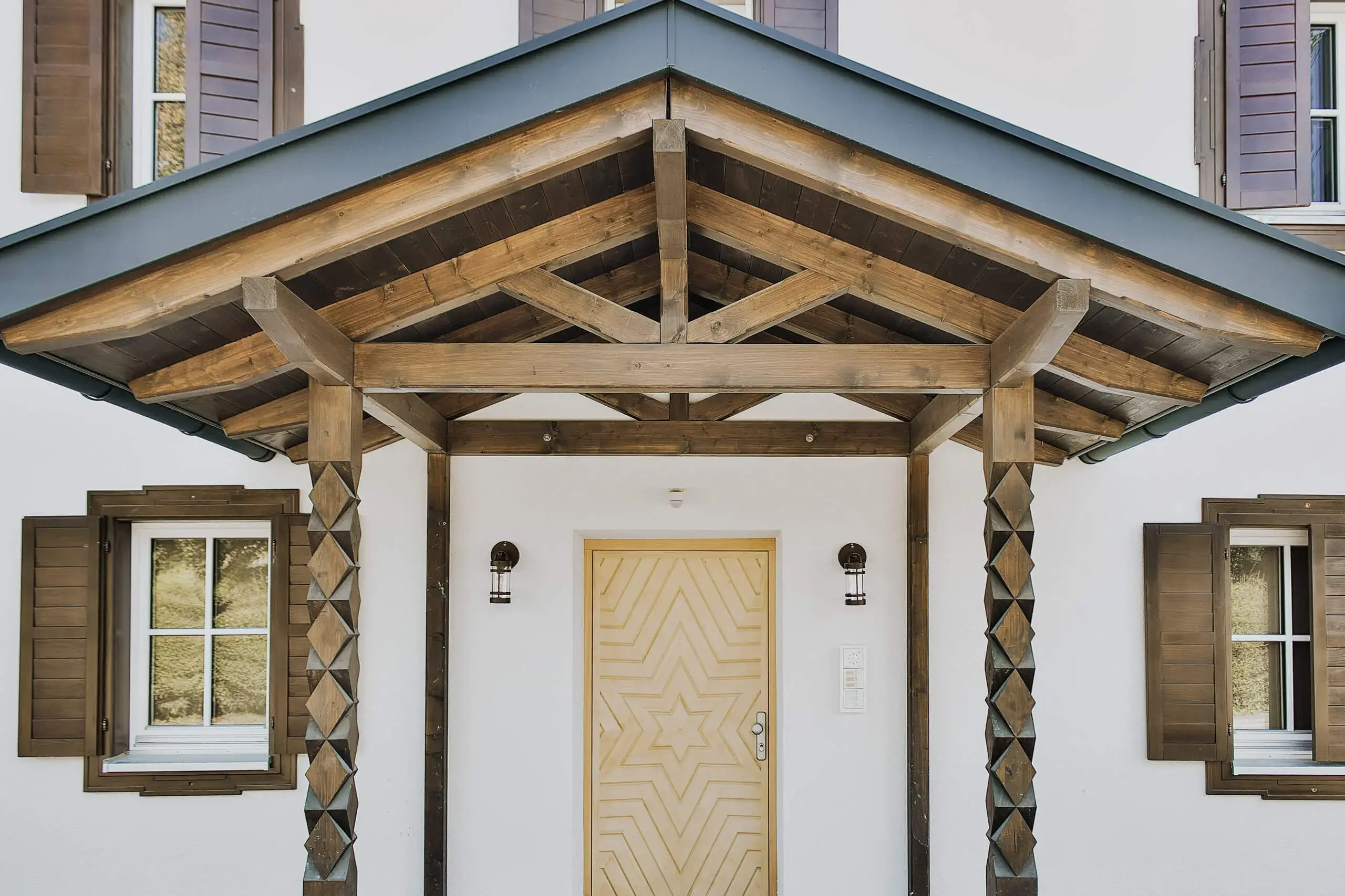 Holzüberdachung von RM Holzbau über einem Hauseingang, schützt vor Sonne und Regen.